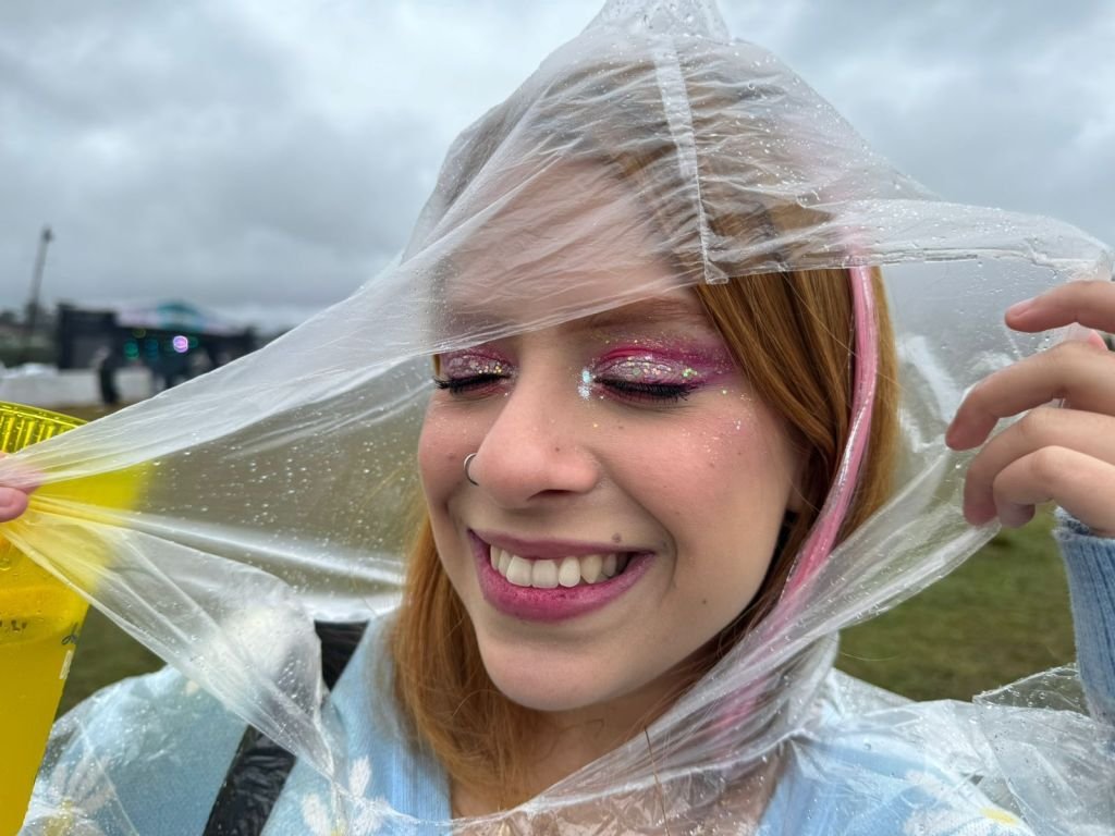 Menina de olhos fechados segurando capa de chuva e mostrando a maquiagem