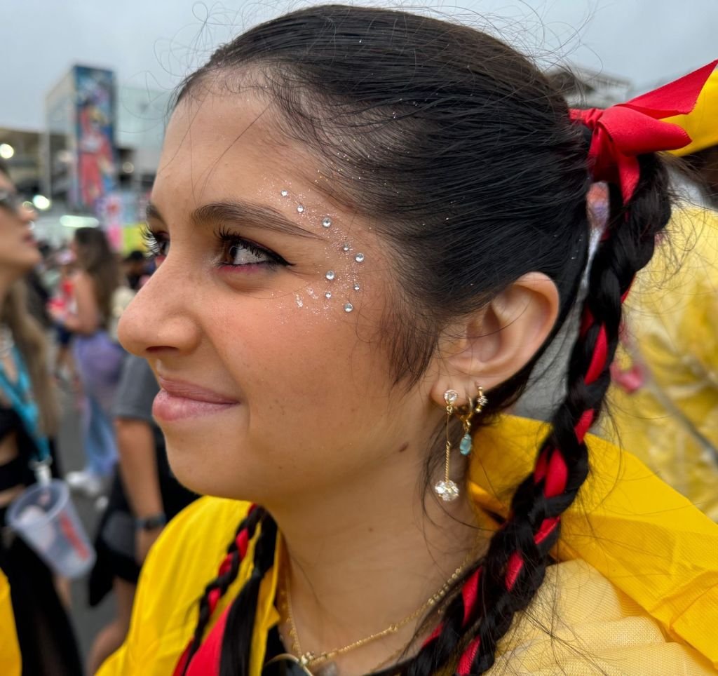 Jovem olha para o lado com maquiagem rosa e glitter prata na lateral do rosto