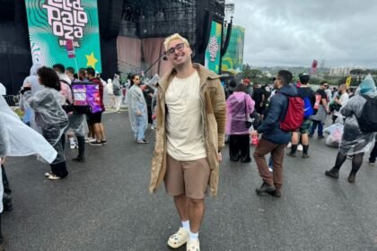 Homem de cabelo descolorido sorrindo em frente ao palco