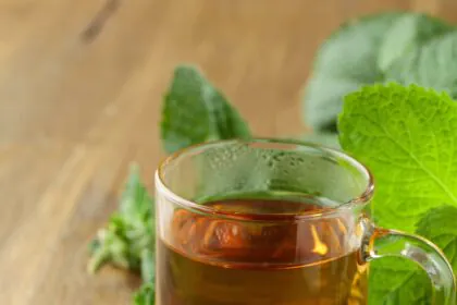 Mint tea in glass on a wooden table.